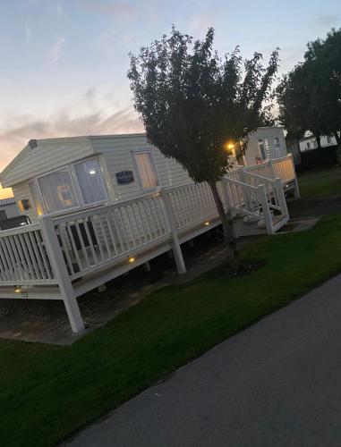 a white house with a porch and a tree at 27 Ivy Close in Mablethorpe