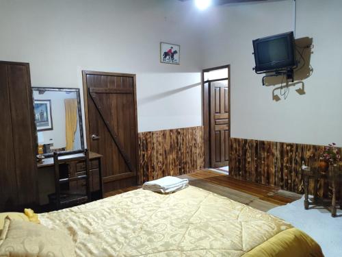 a bedroom with a bed and a tv on the wall at Hostería Tiopullo in Lasso