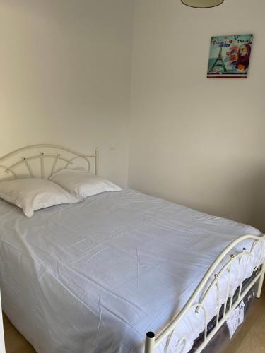 a bed with white sheets and pillows in a bedroom at Maison La Hume climatisée avec piscine et terrasse in Gujan-Mestras