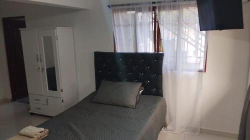 a bedroom with a bed and a window with a pillow at Hostal Villa Laurita in Riofrío