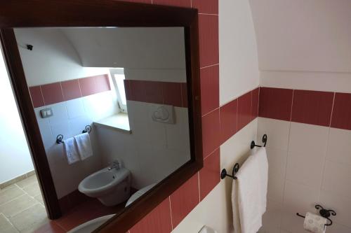 a bathroom with a mirror and a sink and a toilet at Masseria Carignani in Tuglie