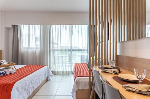 une chambre d'hôtel avec un lit, une table et une fenêtre dans l'établissement Makia Beach Experience- Flat 202D, à Ipojuca