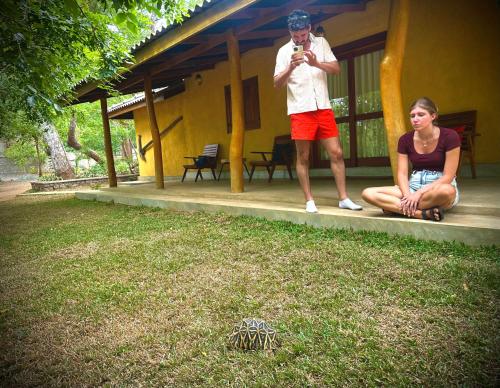 a man and a woman sitting on the porch of a house at Elephant Fence Habarana in Habarana