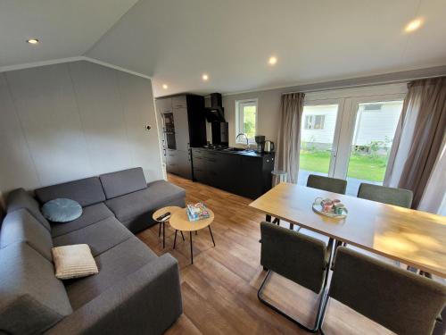 a living room with a couch and a table at Sola Lodge - Luxe chalet in natuur Overijssel in Mariënberg