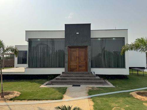 a house with a wooden door in a yard at C-69 Dreamland, Luxury 4BHK farm with private swimming pool , 1 acre garden in Bhundsi