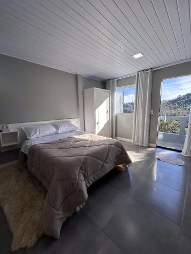 a bedroom with a large bed and a large window at Vista da Serra. in Gramado