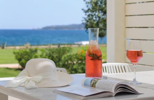 a table with a hat and a drink and a book at Mareggio Exclusive Residences & Suites in Gythio