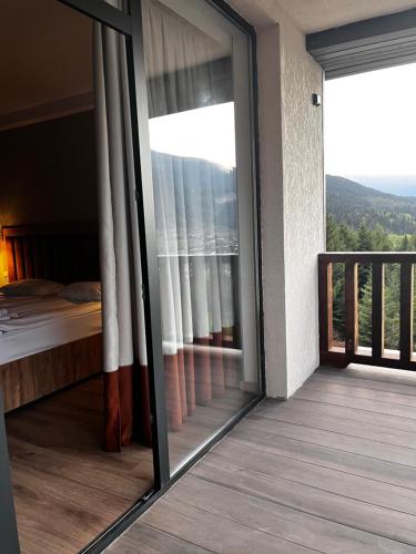 a room with a window with a bed and a balcony at Kakhri Resort in Mestia