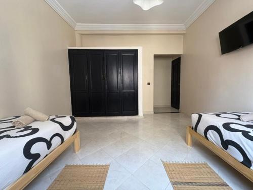 a bedroom with two beds and a television in it at Al Mohit Hôtel Dakhla in Dakhla