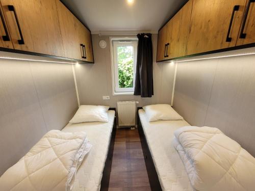 two beds in a small room with a window at Sola Lodge - Luxe chalet in natuur Overijssel in Mariënberg