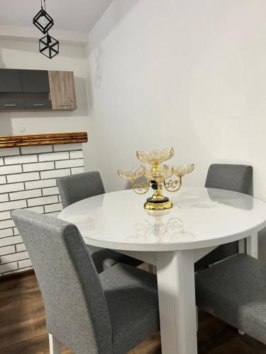 a white dining room table with chairs and a vase on it at Apartman FIKA in Prijepolje