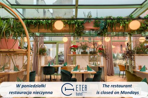 a restaurant with tables and chairs and plants at Hotel ETER in Toruń