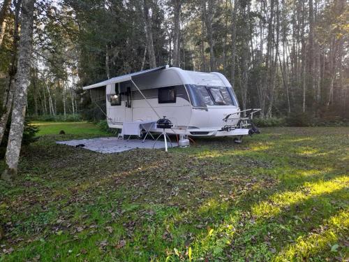 a white caravan parked in a field in a forest at Lonni Nature Eco-Accommodation in Hagudi