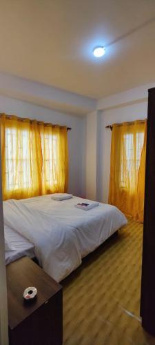 1 dormitorio con 1 cama grande y cortinas amarillas en The River View Crescent, en Kurseong