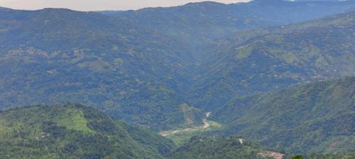 vistas a un valle de montaña con una carretera sinuosa en The River View Crescent, en Kurseong
