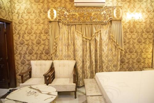a room with two chairs and a curtain at The Red Tree II Executive Guest House in Karachi