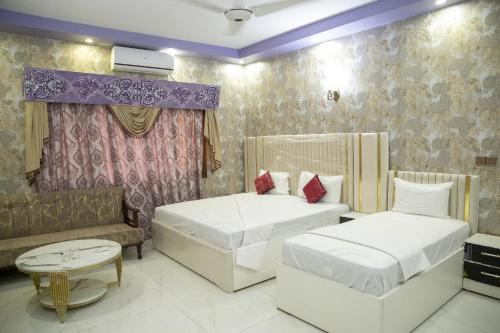 a bedroom with two beds and a couch at The Red Tree II Executive Guest House in Karachi
