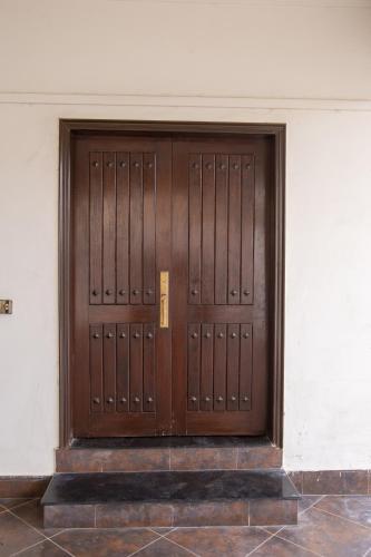 a pair of wooden doors in a building at The Red Tree II Executive Guest House in Karachi
