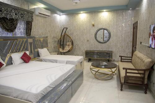 a bedroom with two beds and a table and a mirror at The Red Tree II Executive Guest House in Karachi