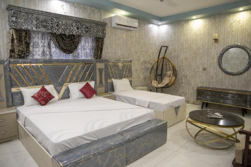 a bedroom with two beds and a table at The Red Tree II Executive Guest House in Karachi