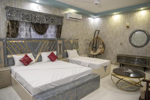 a bedroom with two beds and a table at The Red Tree II Executive Guest House in Karachi
