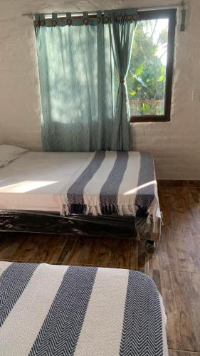 a bed in a room with a window and a bedskirtspectspectspectspects at Ecopolis Hospedaje en el queremal in Papagalleros