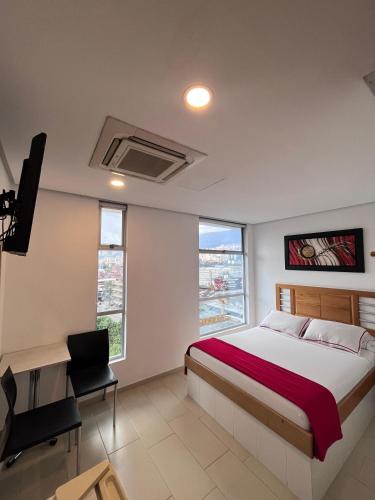a bedroom with a bed and a desk and some windows at Hotel Portal Central in Medellín