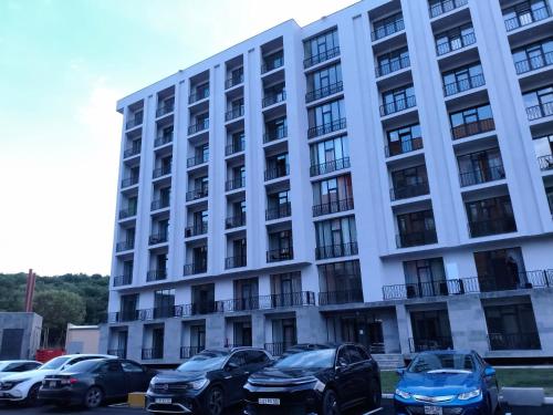 a large white building with cars parked in a parking lot at Alvina 2 apartment hotel Tsaghkadzor in Tsaghkadzor