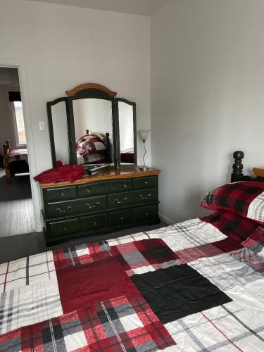 a bedroom with a bed and a dresser with a mirror at Grand logement chaleureux in La Tuque