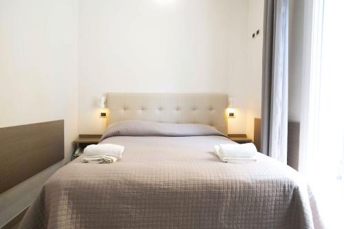 a bedroom with a large bed with two towels on it at Hotel Sant'Elena in Rimini