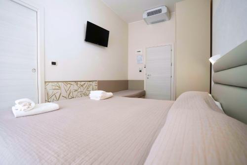 a bedroom with a white bed with towels on it at Hotel Sant'Elena in Rimini