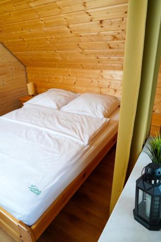 a bed in a room with a wooden ceiling at Leśny Zakątek in Bezmichowa Dolna