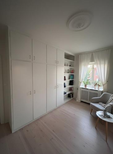a living room with white cabinets and a table at Cosy City Apartment in Odense