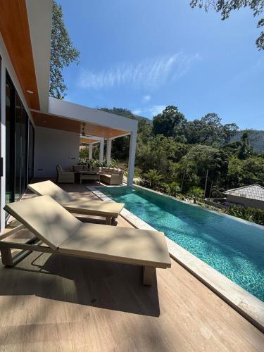 a swimming pool with chaise lounge chairs next to a house at Villa Thai Sabai 2, Lamai in Lamai