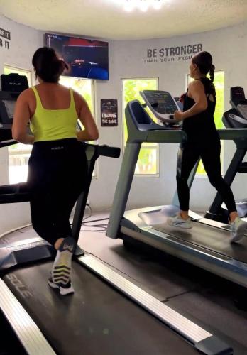 two women running on a treadmill in a gym at Best Western Grand Baymen Gardens in San Pedro