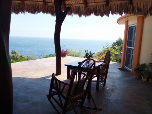 a table and chairs on a patio with a view of the ocean at Angelita's Nest House in Puerto Ángel