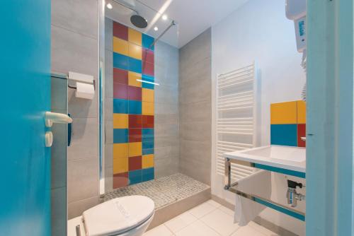 uma casa de banho com um WC e um chuveiro colorido. em Hôtel L'Océane em Andernos-les-Bains