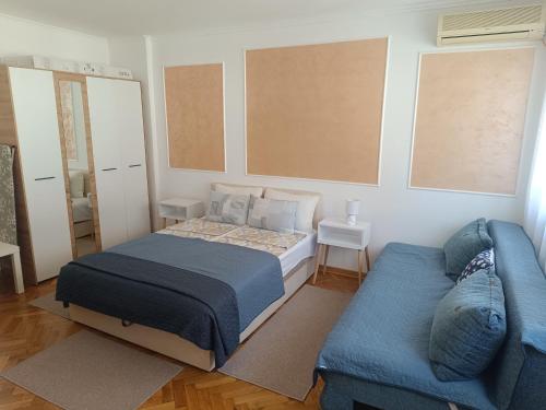 a bedroom with a bed and a blue couch at Apartman Nicolas in Karaburma