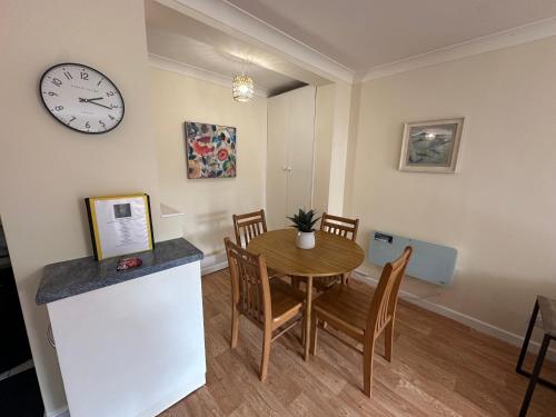 a dining room with a table and a clock on the wall at Ely Stays Flat 2 City Center in Ely