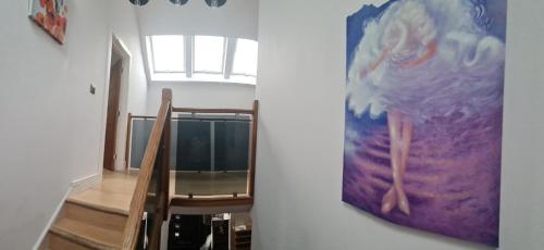 un dipinto su un muro accanto a una scala con una sedia di Newquay Beach Ocean Heights Villa a Newquay