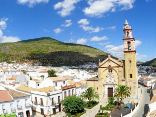 a church in a town with a hill in the background at La BODEGA DE ROSARIO in Algodonales