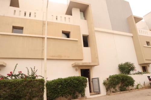 a white building with bushes in front of it at Surf and Stay Villa Anza Taghazout Tamraght in Agadir