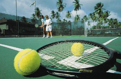 two tennis balls on a tennis racket on a court at Coyaba Beach Resort in Saint Georgeʼs