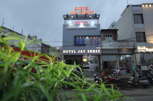 ウッジャインにあるHotel Jay Shreeのホテルのある建物と、その前にバイクが並ぶ通り