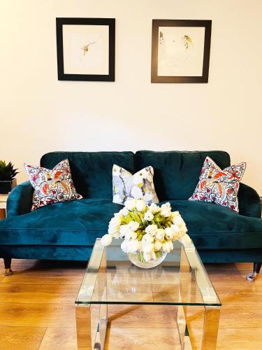 a living room with a blue couch and a glass table at 2-Bed Apartment Near ExCeL - Free Parking & WiFi - Ideal for Families, Business & Leisure in London