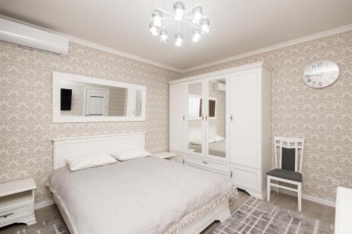 a bedroom with a bed and a chair and a clock at Aparthotel Royal Status in Chişinău