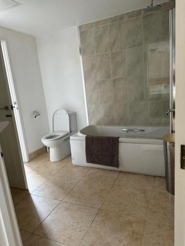 a bathroom with a toilet and a tub and a sink at Beautiful Barn Conversion Wyboston in Bedford