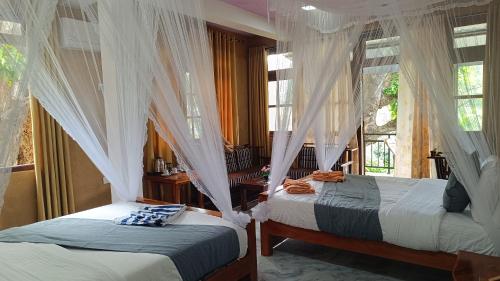 a bedroom with two beds and windows with curtains at Forest Rawana homestay Ella in Ella