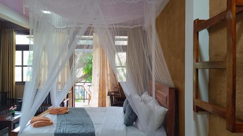 a bedroom with a canopy bed with a window at Forest Rawana homestay Ella in Ella