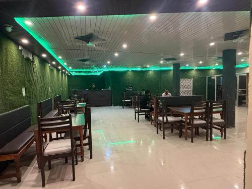 a restaurant with wooden tables and chairs and green lights at Riddhi kitchen in Silao